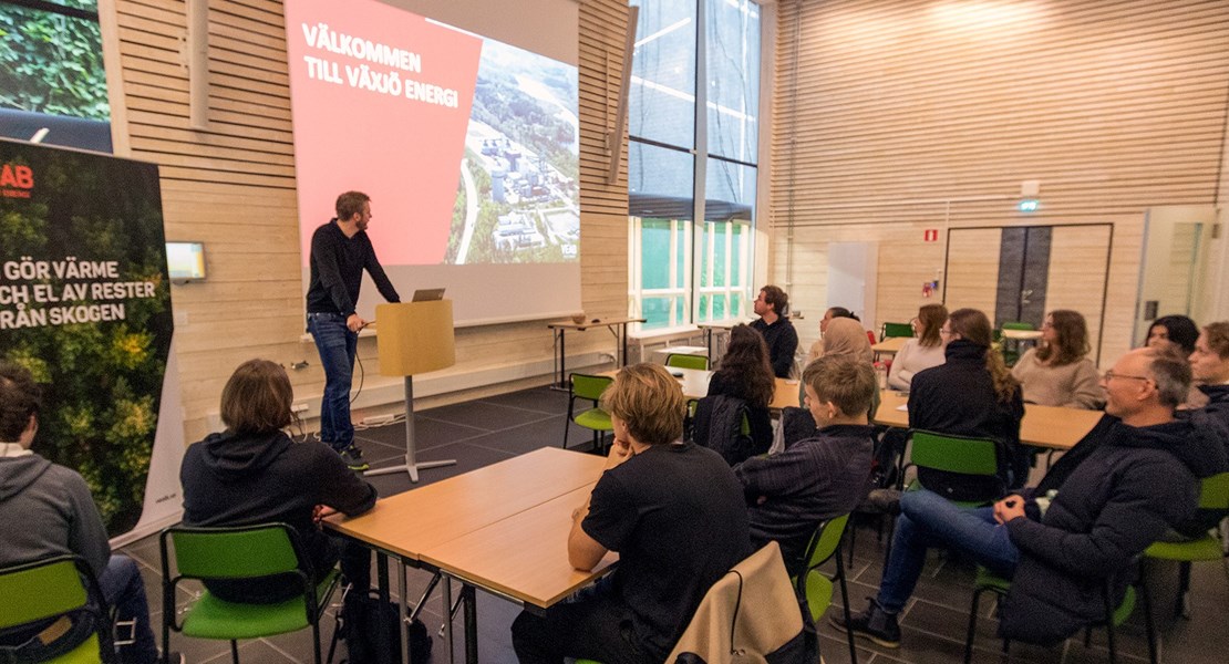 Några personer sitter i ett konferensrum och tittar mot en presentation