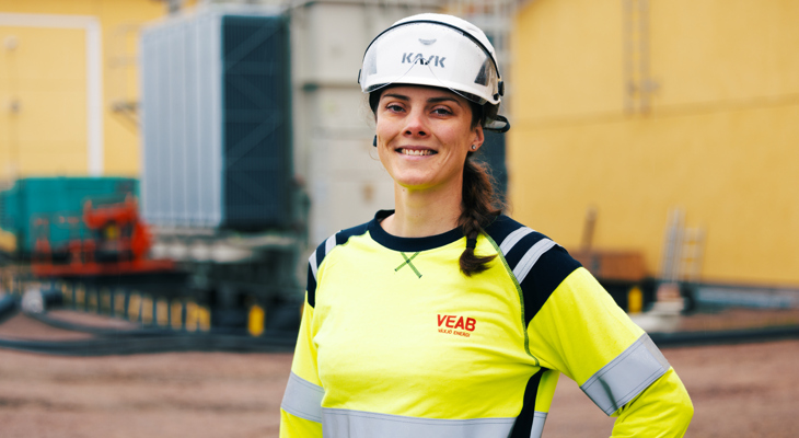 Medarbetaren Tina står i gul tröja och tittar in i kameran